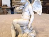 une photo représentant la statue d'un enfant assis sur une table