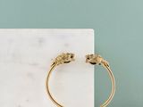 Le bracelet manchette en or est orné de deux petits éléphants