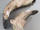 pair of wooden dolphins with holes in their mouths on a gray surface