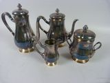 three pieces of silver tea and coffee set on a white surface