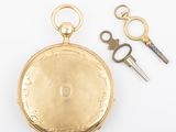 a gold pocket watch with a pair of scissors next to it