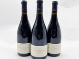 trois bouteilles de vin sont posées sur une surface blanche, devant un fond blanc