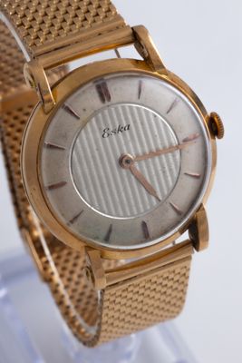 a gold wrist watch on display on a clear stand
