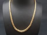 un collier en or autour du cou d'un mannequin, sur fond noir