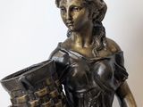 bronze statue of a woman holding a basket of flowers