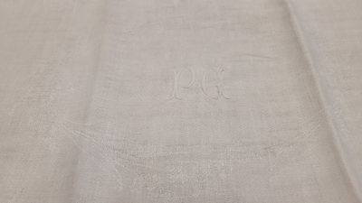 un gros plan sur une nappe blanche ornée d'un monogramme