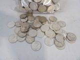 a bag of silver coins sitting on a table next to a pile of silver coins
