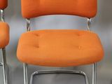 three orange chairs sitting next to each other on a white surface