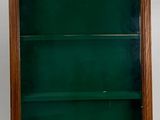 an old wooden bookcase with a green glass door