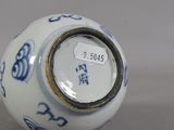 a white and blue vase on a table with a tag on it