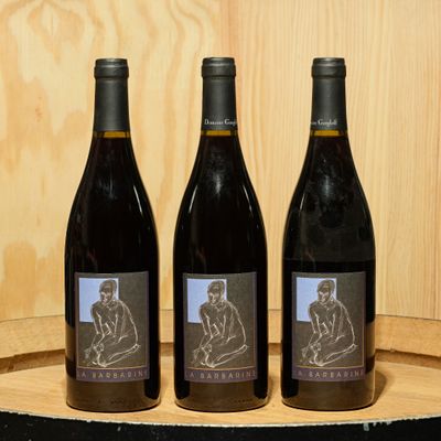 three bottles of wine sitting on top of a wooden barrel