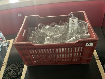 un panier rouge rempli de bouteilles en verre vides posé sur une table