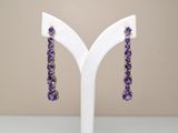 Des boucles d'oreilles ornées d'améthorate et de perles d'améthorate sont présentées sur un présentoir blanc