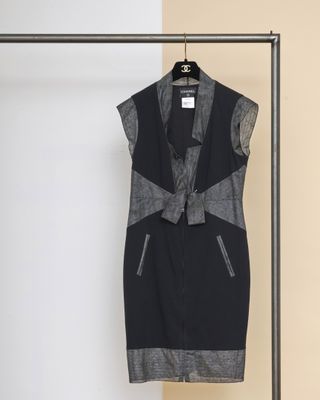 une robe noire et grise suspendue à un cintre devant un mur blanc