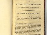 un livre ouvert posé sur une table blanche, sur lequel est accrochée une étiquette