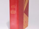 an old red book sitting on top of a table next to a white wall