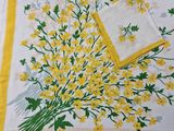 yellow and green flowers on a white table cloth with a yellow napkin