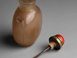 a small jar of liquid next to a spoon on a table