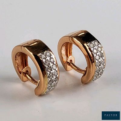 une paire de boucles d'oreilles créoles en or et diamants sur fond blanc