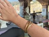 a woman ' s hand that is holding a gold bracelet