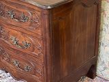 a wooden chest of drawers on a rug in front of a wall