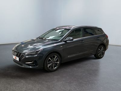 Une voiture grise est garée dans une pièce blanche au sol noir.