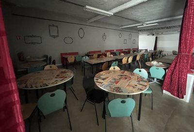 many tables and chairs in a room with a red curtain