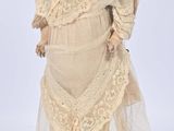 an old fashioned doll with a white dress and lace on it