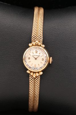 a close up of a gold wrist watch on a black cushion