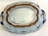 une assiette bleue et blanche à bord brun posée sur une table blanche