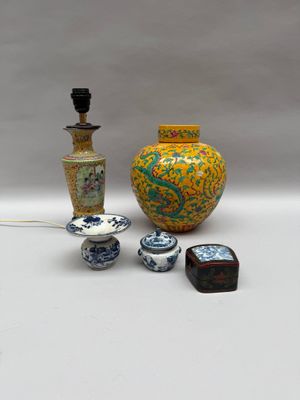 un vase jaune, un vase bleu et blanc et une lampe noire posés sur une table blanche