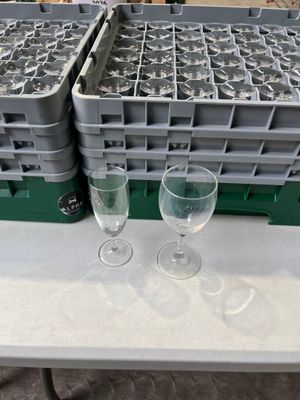 deux verres à vin vides posés sur une table, à côté d'un porte-verres contenant des verres à vin vides