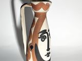 a vase with a face painted on it sitting on a table