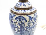 un vase bleu et blanc posé sur une table sur laquelle se trouve une lampe