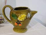 a green vase with a design on it sitting on a table