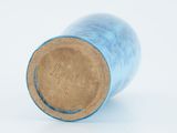 a blue vase with a brown lid sitting on a white surface