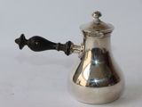 a silver coffee pot with a black handle on a white table