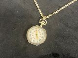 an image of a gold necklace with a pocket watch attached to it