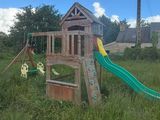 a wooden swing set in the middle of a grassy field