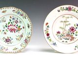 two plates with floral designs are sitting side by side on a white surface