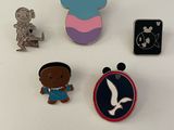 trois pin's Disney sont posés sur une surface blanche