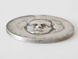an image of a silver coin with a face of a man on it