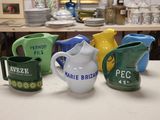 many different colored pitchers sitting on a table