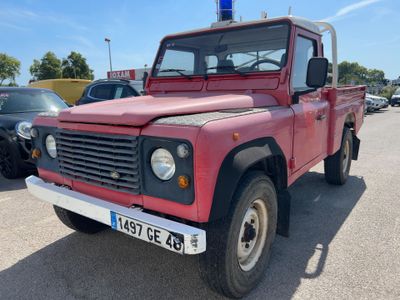 a red truck parked in a parking lot next to other cars