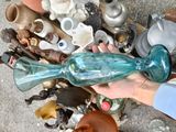 a person holding a blue glass fish on a pile of other items