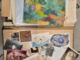 une valise remplie d'œuvres d'art et de papiers posée par terre