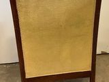 the back of a wooden chair with a tan upholstered seat