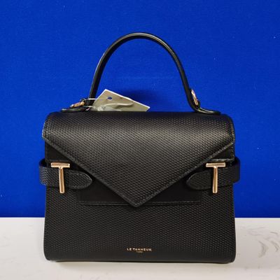 a black handbag sitting on top of a table next to a blue wall