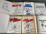 six books of comics are lined up on a table
