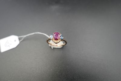 une photo d'une bague sertie d'un saphir rose et de diamants, posée sur une surface noire